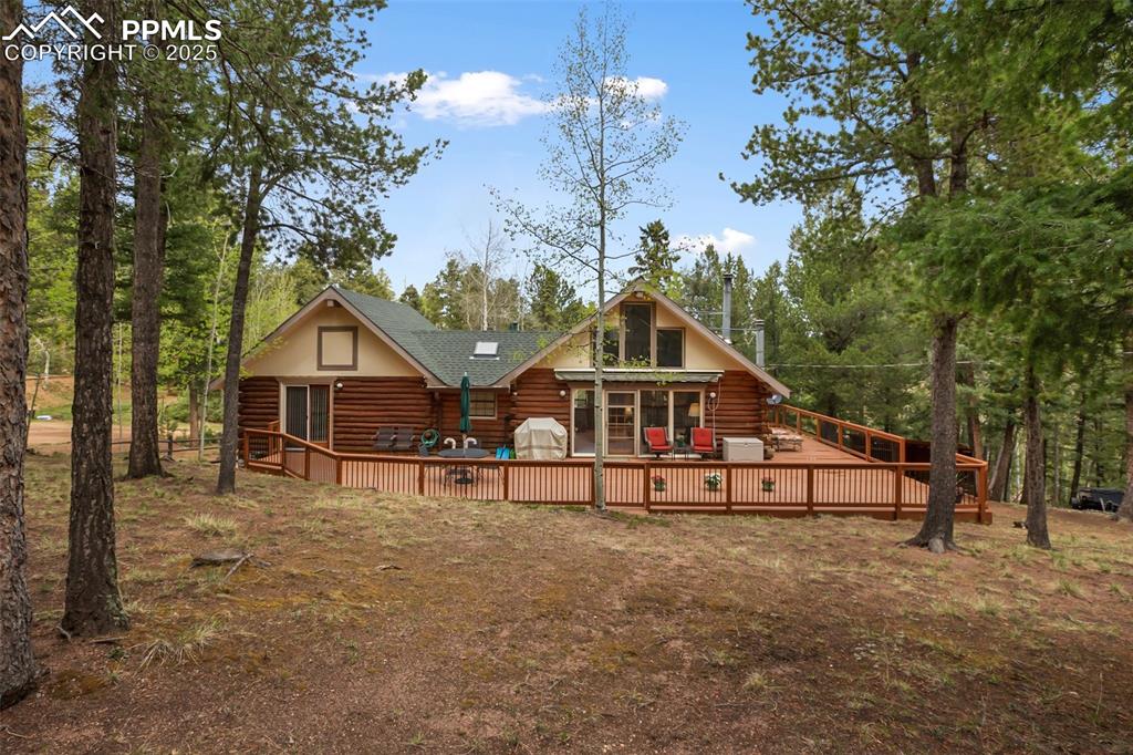 Image 7 of 36: Rear view of property with log exterior, a deck, and roof with shingles