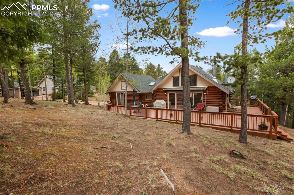 Image 8 of 36: Rear view of house featuring log exterior and a deck