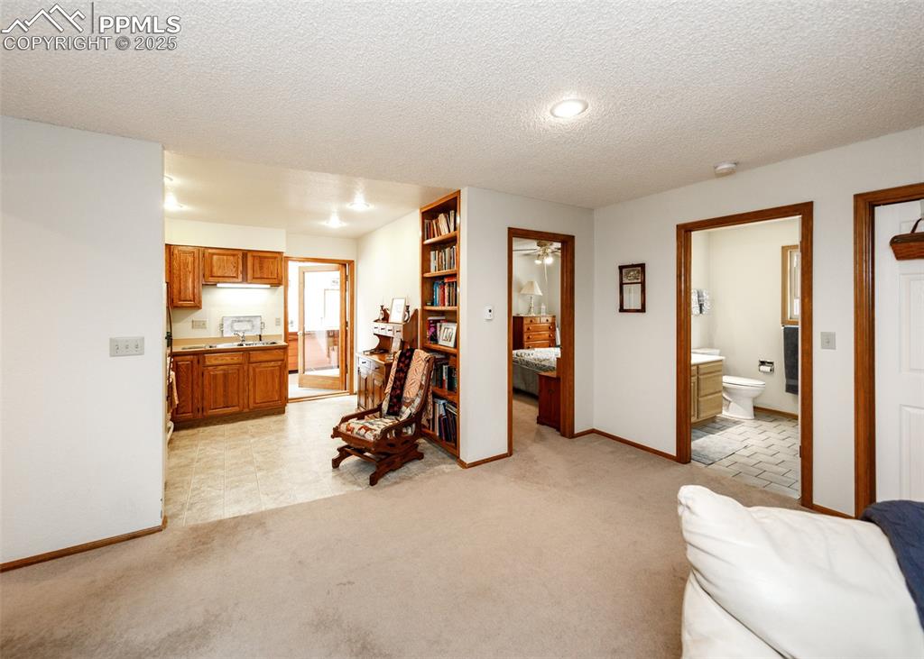 Image 12 of 41: Living area in Mother in law suite featuring a textured ceiling, light carp