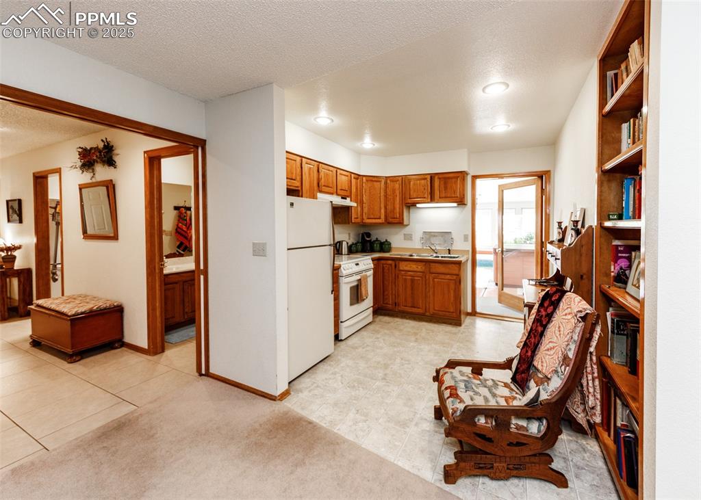 Image 13 of 41: second kitchen in Mother in law suite featuring brown cabinetry, white appl