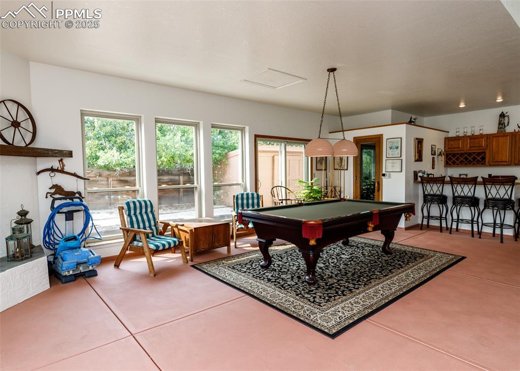 Image 21 of 41: Indoor pool room with billiards table, bar area, and light tile patterned f
