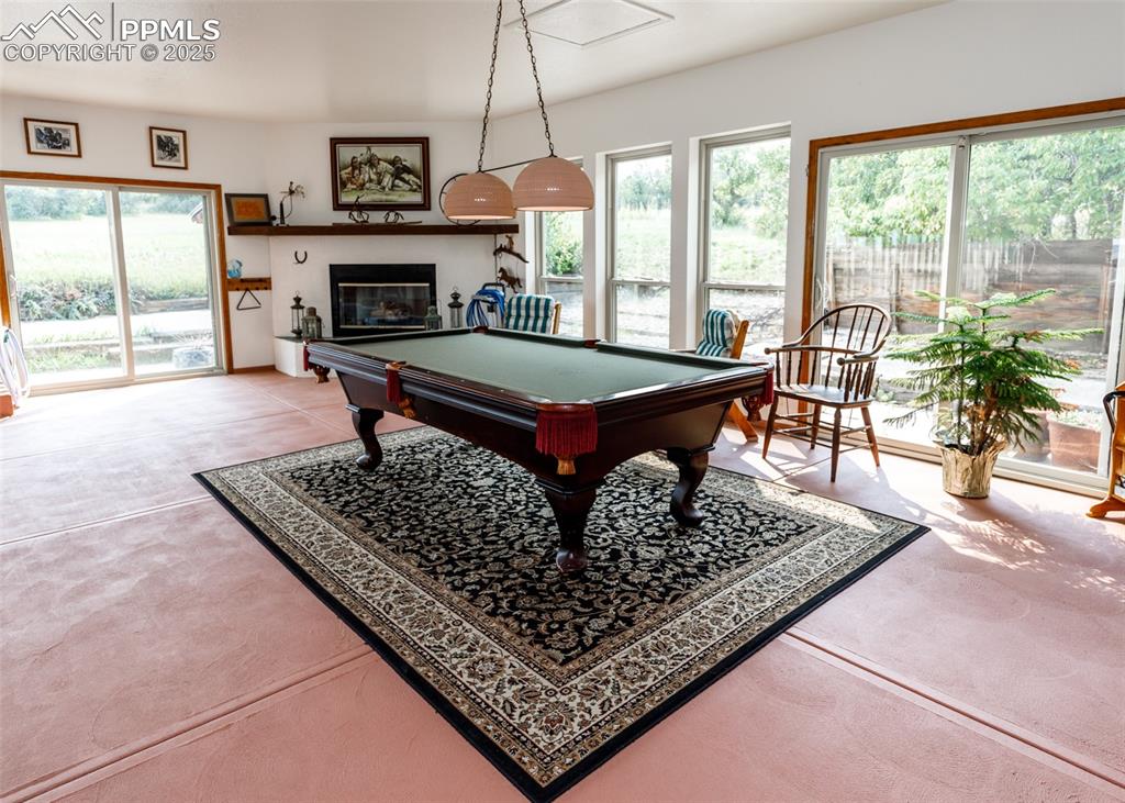 Image 22 of 41: Indoor pool room with billiards table and a glass covered fireplace