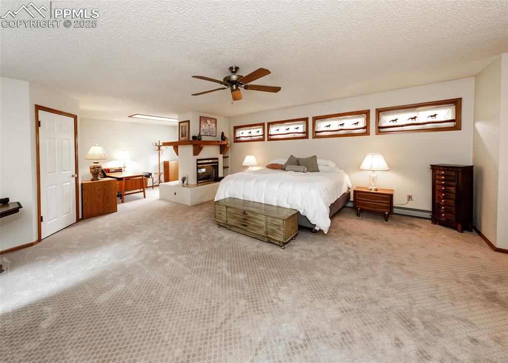 Image 25 of 41: Carpeted master bedroom with a textured ceiling, a multi sided fireplace, a