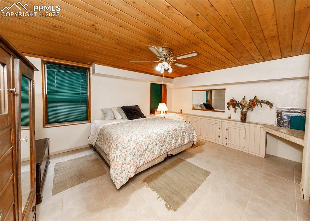 Image 29 of 41: Basement Bedroom with ceiling fan, light tile patterned floors, and wooden