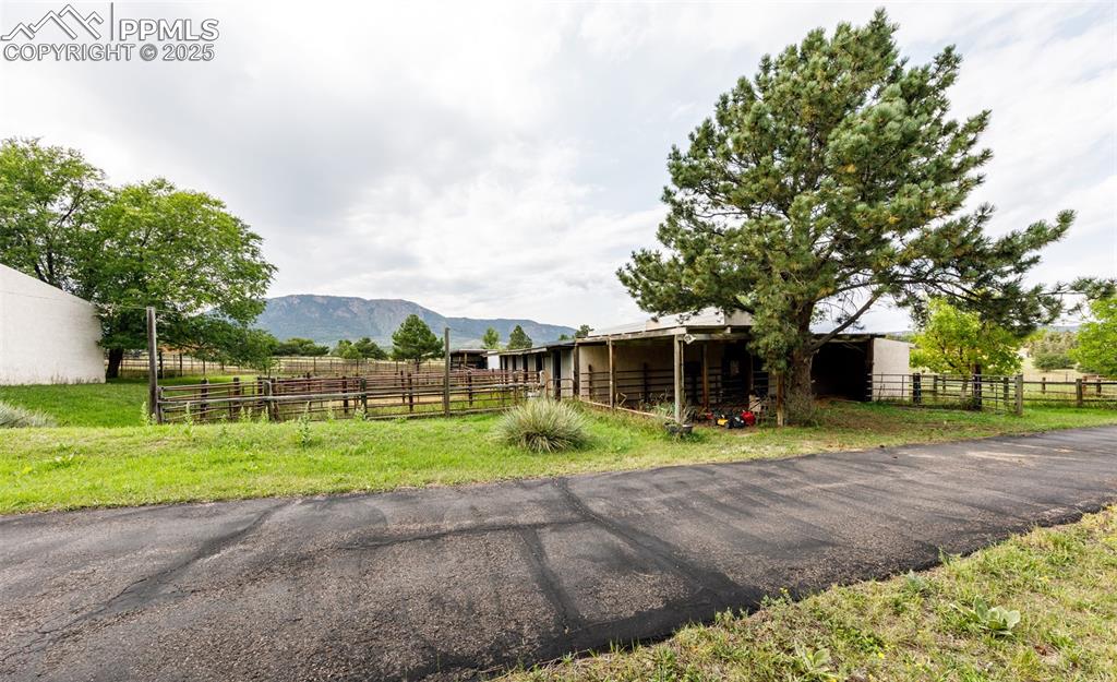 Image 33 of 41: View of asphalt driveway featuring a mountain view, an exterior structure,