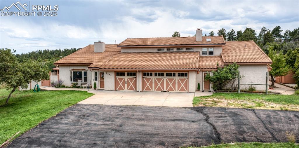Image 4 of 41: Mediterranean / spanish-style house with a chimney, driveway, a front lawn,