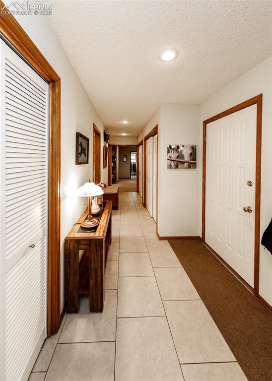 Image 7 of 41: Hall with a textured ceiling, light tile patterned floors, and recessed lig