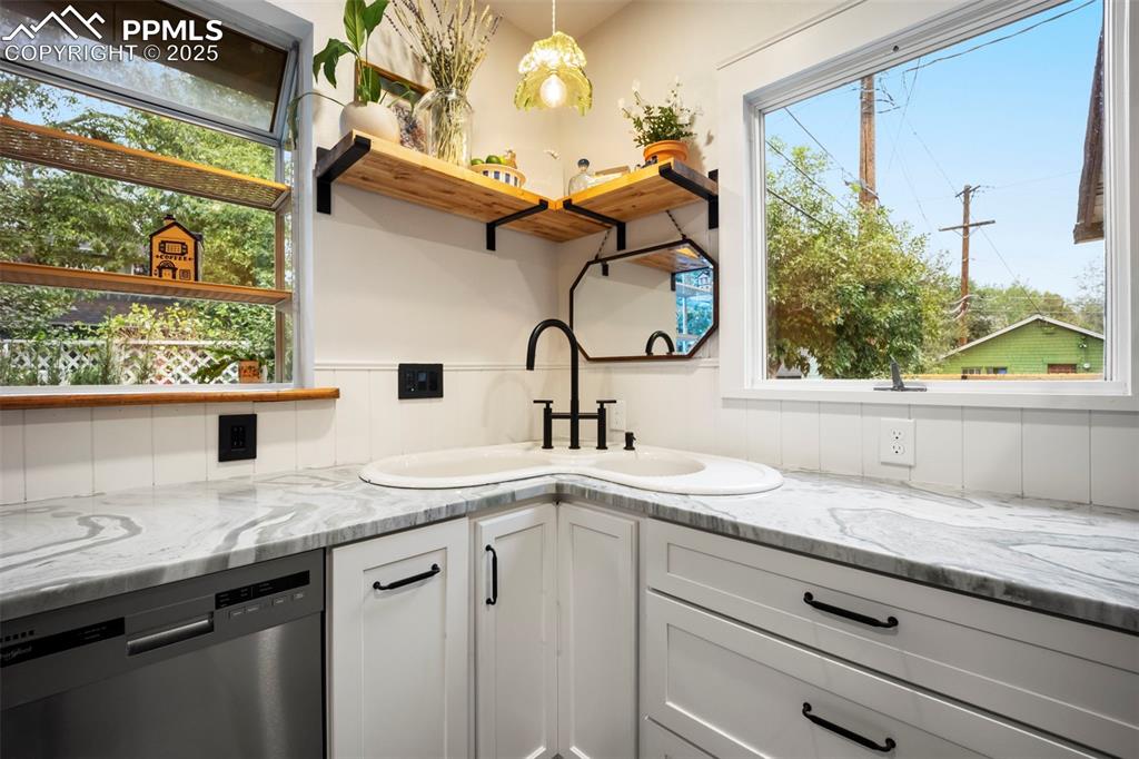 Image 13 of 48: Kitchen featuring open shelves, light stone countertops, stainless steel di