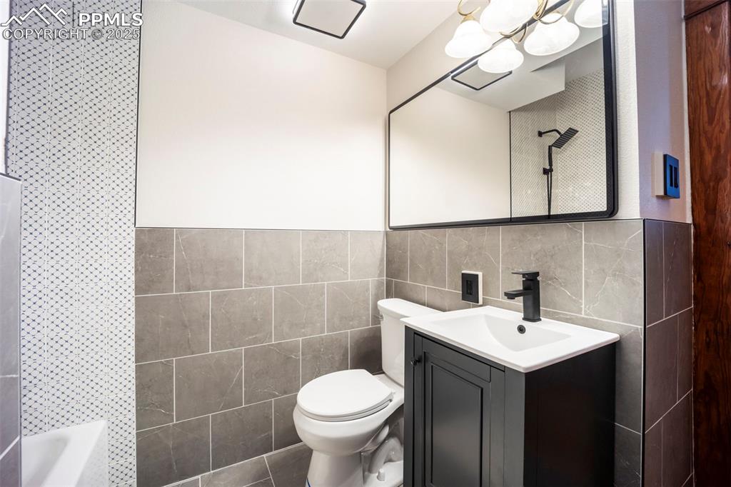 Image 17 of 48: Full bathroom with tile walls, vanity, and shower / bath combination