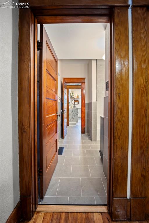 Image 21 of 48: Corridor featuring wood finished floors and tile walls