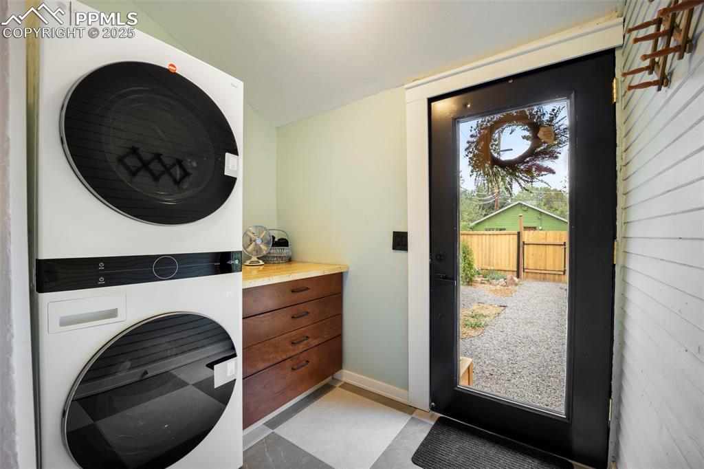 Image 23 of 48: Washroom with stacked washer and clothes dryer and light tile patterned flo