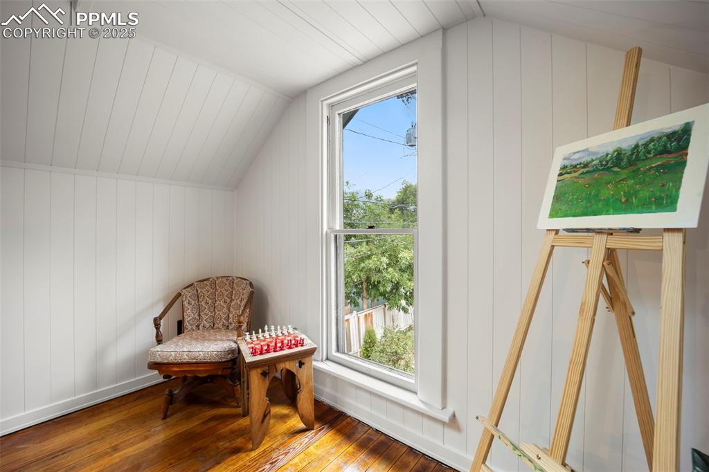 Image 26 of 48: Living area with hardwood / wood-style floors, vaulted ceiling, and wood wa