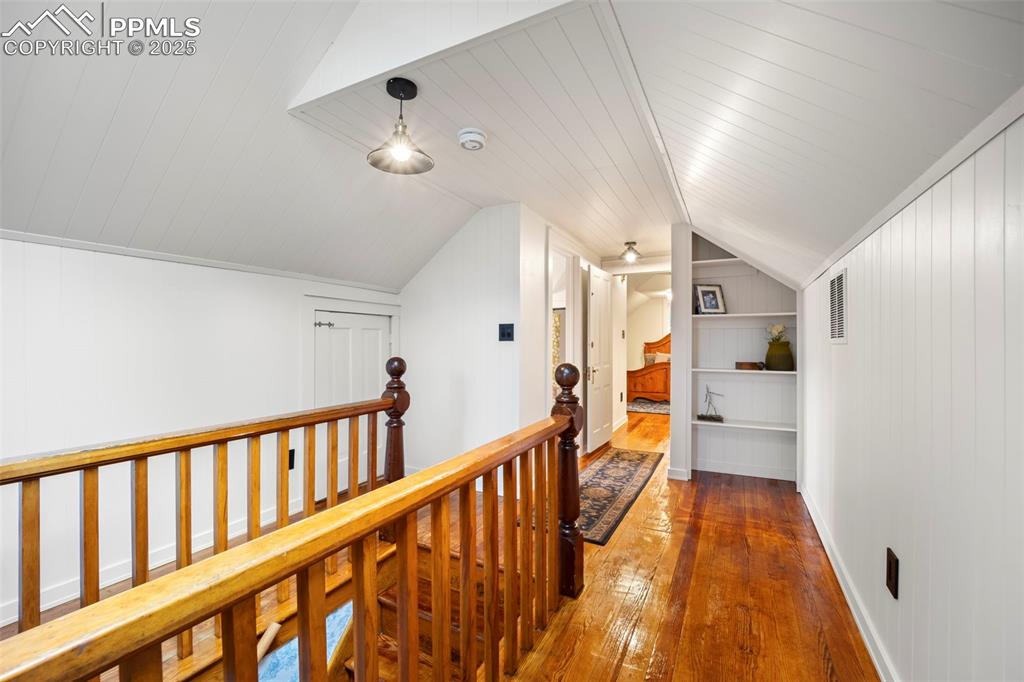 Image 27 of 48: Hallway featuring hardwood / wood-style floors, lofted ceiling, and built i