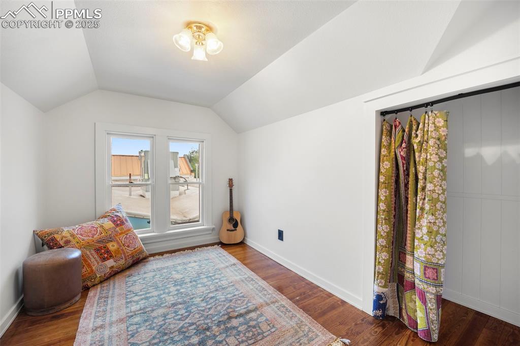 Image 28 of 48: Sitting room with dark wood-style floors and vaulted ceiling