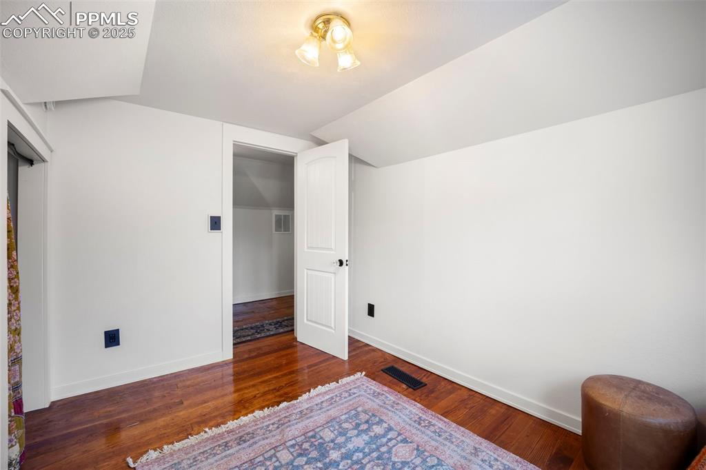 Image 29 of 48: Bedroom with dark wood-style floors and vaulted ceiling