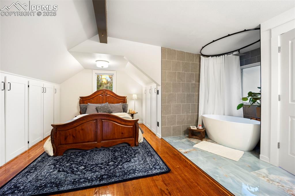Image 30 of 48: Bedroom featuring wood finished floors and tile walls