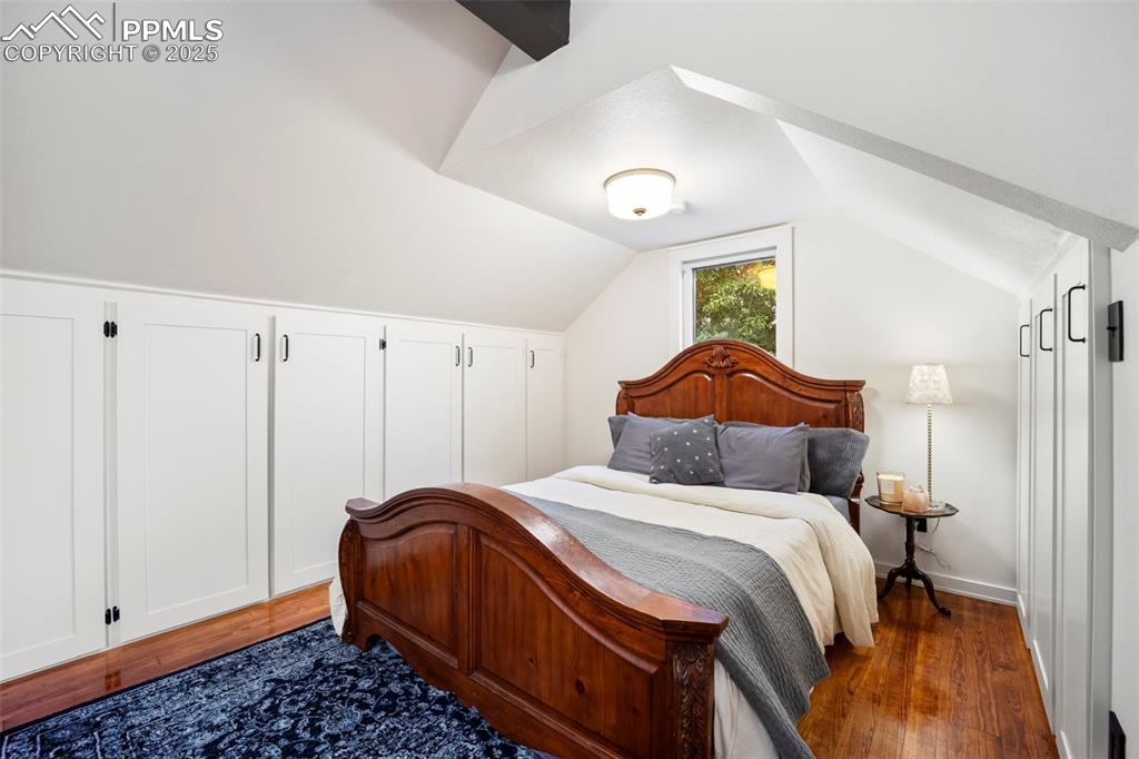 Image 32 of 48: Bedroom with dark wood-style floors and lofted ceiling