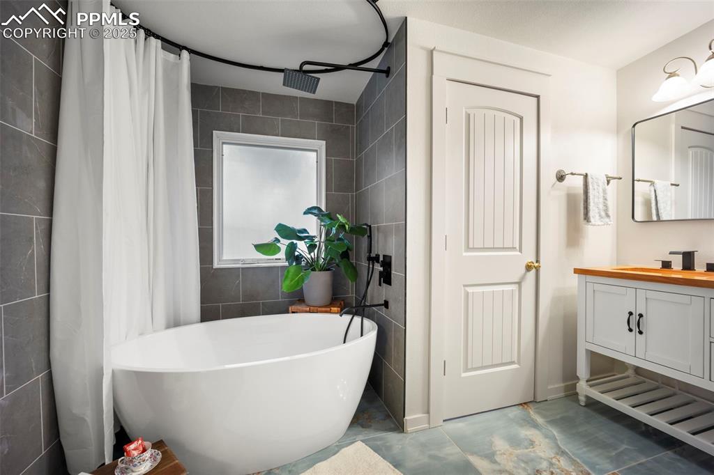 Image 33 of 48: Full bathroom with a freestanding tub, vanity, tile walls, curtained shower