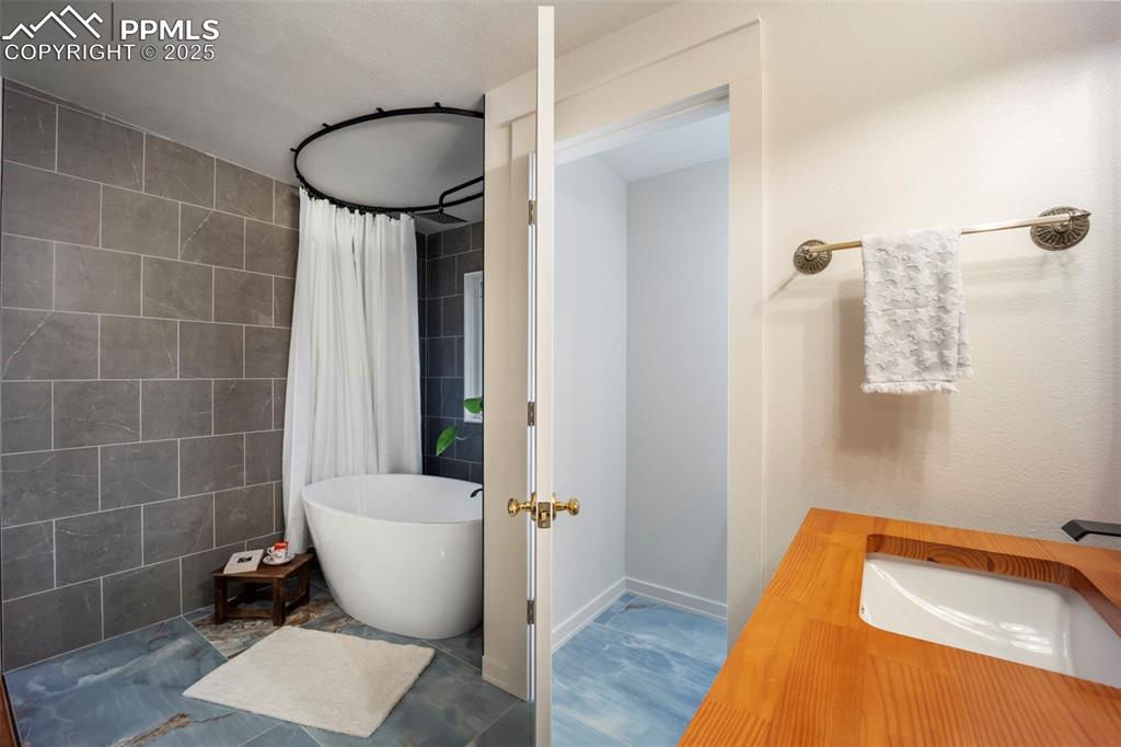 Image 34 of 48: Bathroom featuring vanity, tile walls, and a combined bath / shower with fr