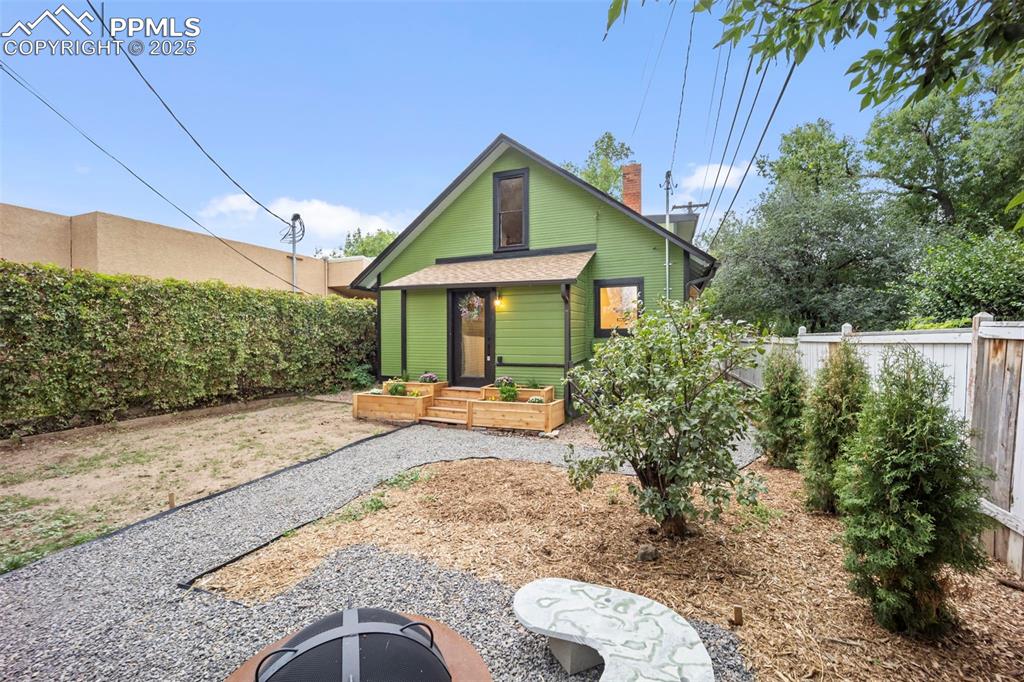 Image 35 of 48: Back of house featuring a fenced backyard and a chimney