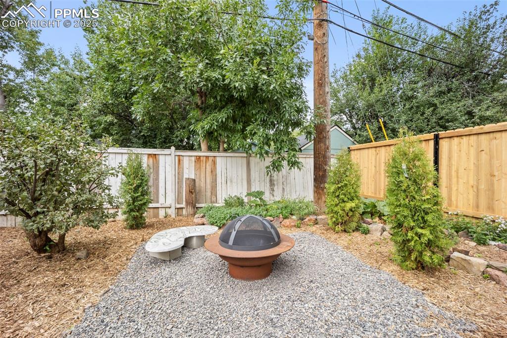 Image 37 of 48: Fenced backyard with a fire pit