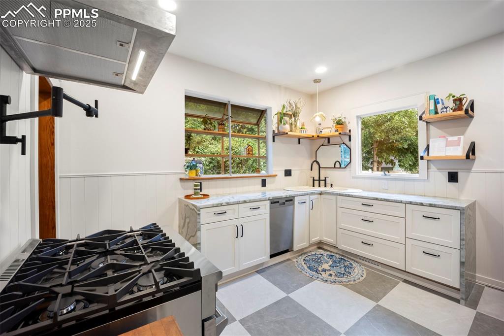 Image 9 of 48: Kitchen with a wainscoted wall, range hood, white cabinets, stainless steel