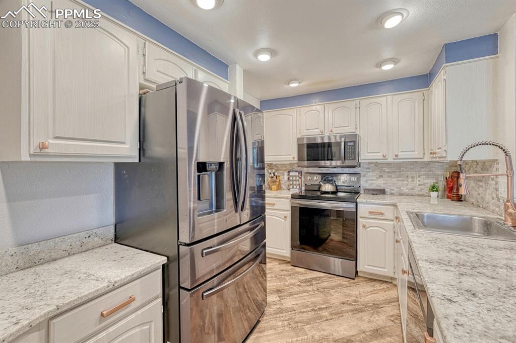 Image 7 of 48: Kitchen with LVP, granite countertops, travertine backsplash