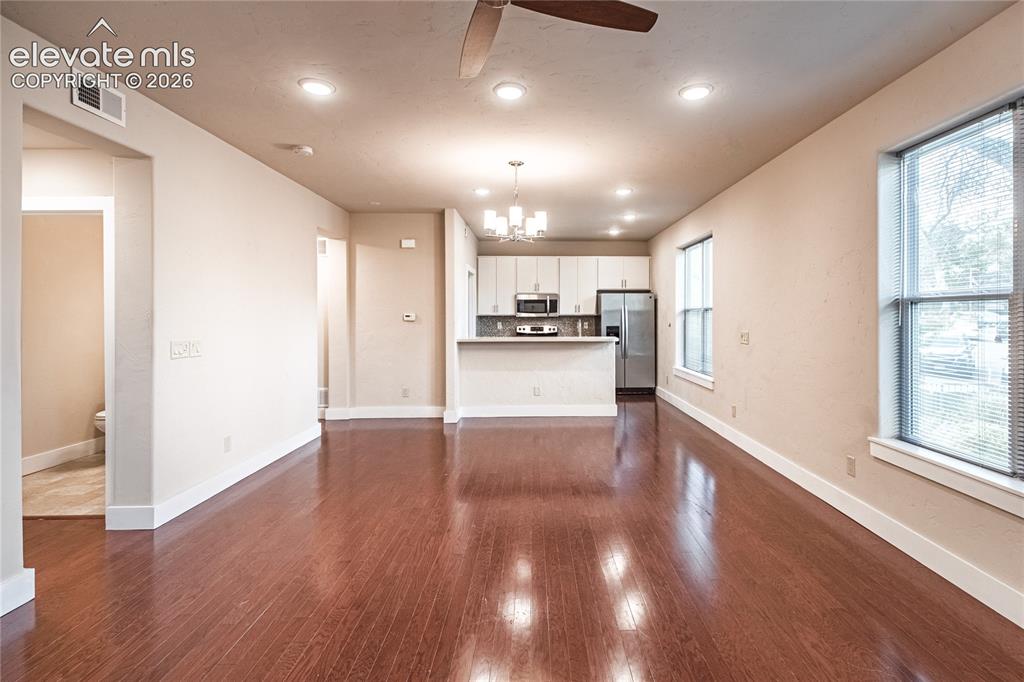Image 10 of 50: Expansive open-concept living area featuring rich wood-finish flooring, rec