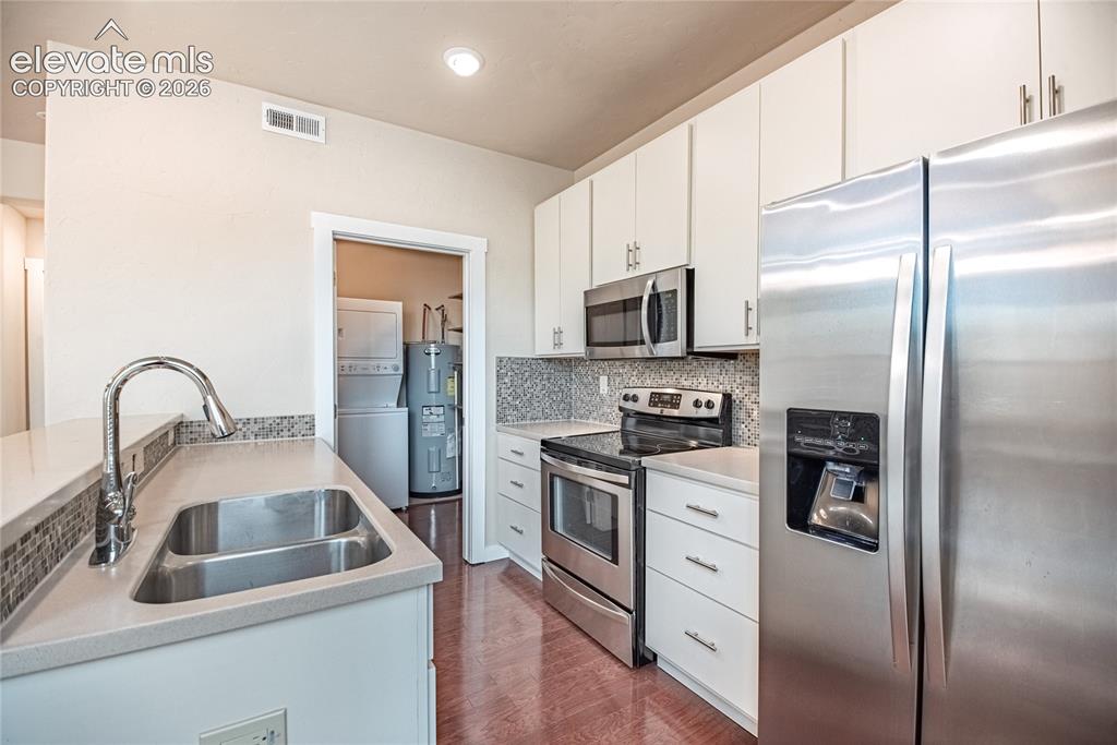 Image 13 of 50: Kitchen featuring stainless steel appliances, white cabinetry, a double bas