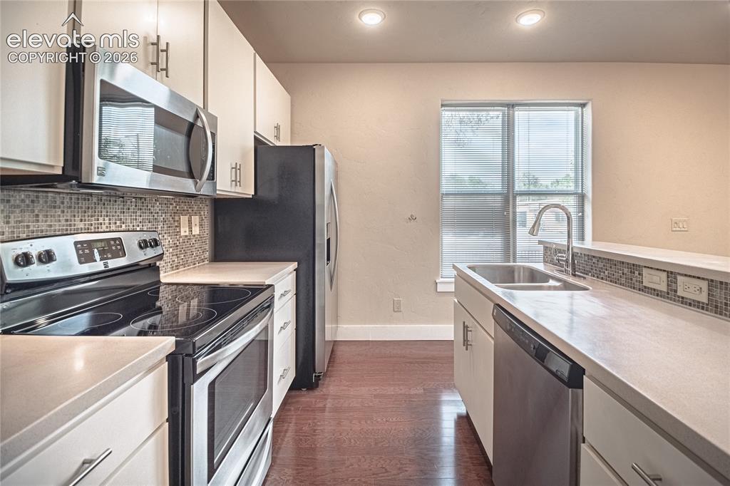 Image 14 of 50: Contemporary kitchen featuring stainless steel appliances, mosaic tile back