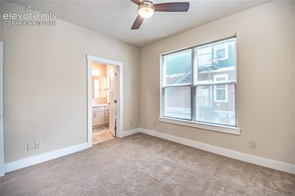 Image 18 of 50: Carpeted room featuring a ceiling fan with light fixture, a large window wi