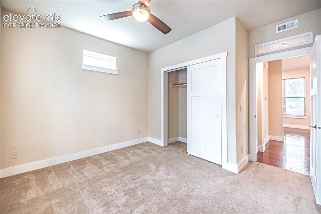 Image 19 of 50: Carpeted room with a ceiling fan, a high-set window, and a white sliding cl