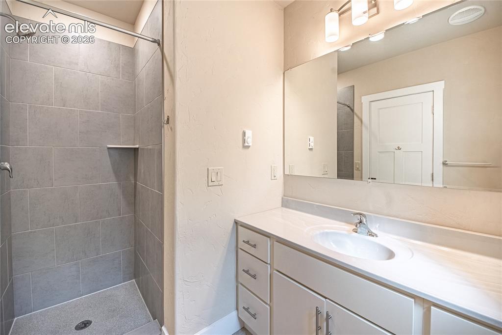 Image 22 of 50: Bathroom featuring a walk-in shower with large format grey tile, a built-in