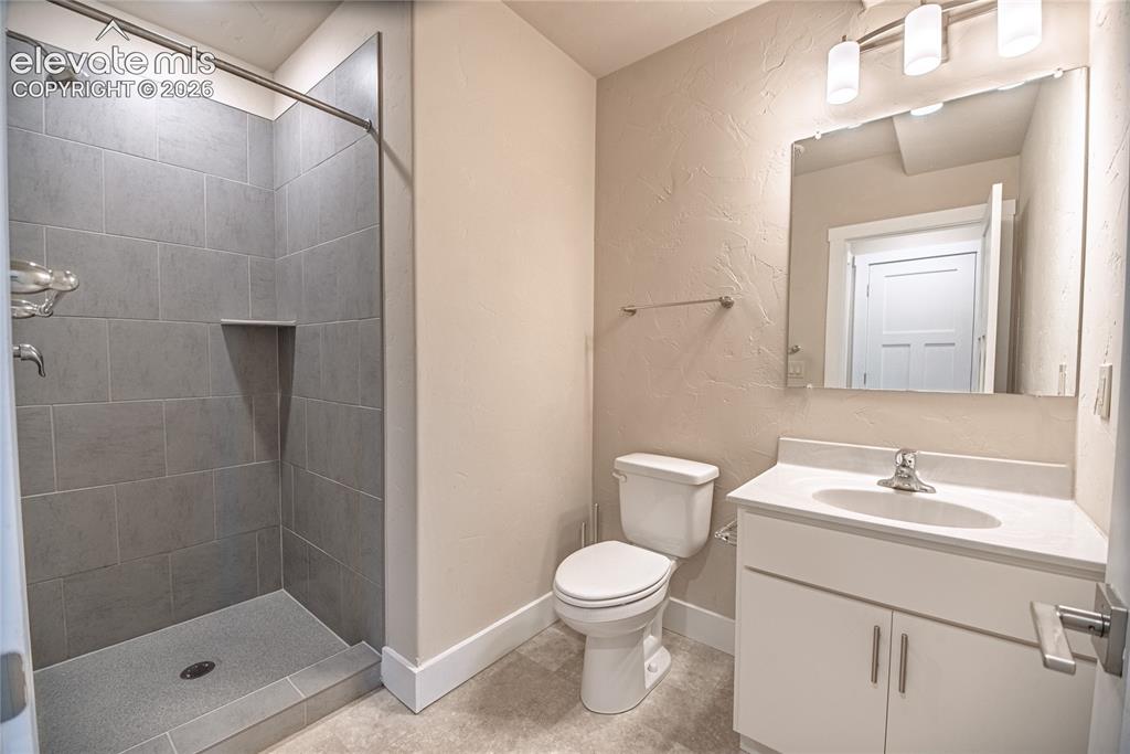 Image 25 of 50: Bathroom featuring a tiled shower with a built-in niche, white vanity with