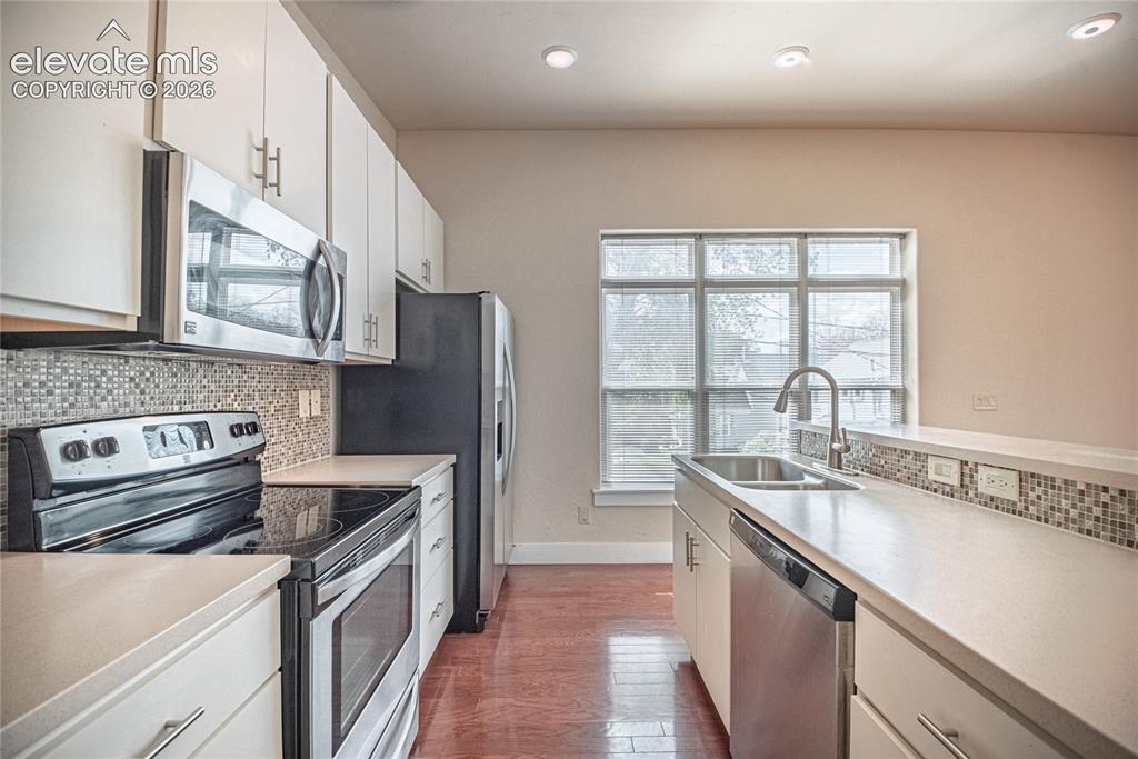 Image 30 of 50: Kitchen featuring light cabinetry, stainless steel appliances, mosaic tile