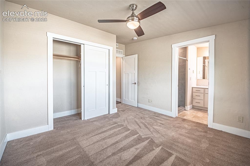 Image 35 of 50: Carpeted room with a ceiling fan, featuring a sliding closet door and an en
