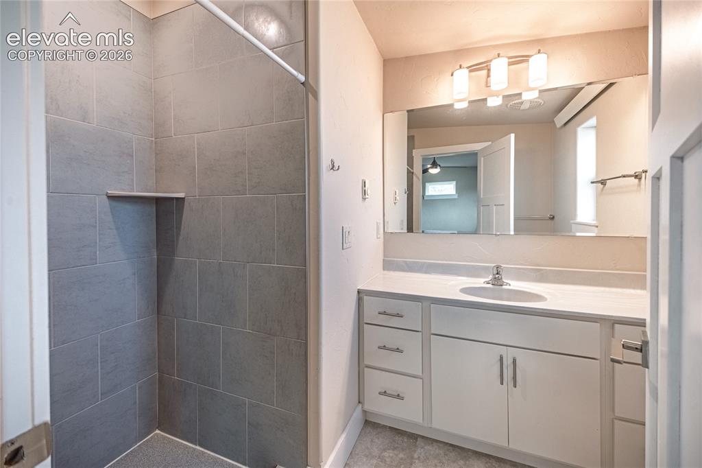 Image 37 of 50: Bathroom vanity featuring a single sink, white cabinetry with silver-tone h