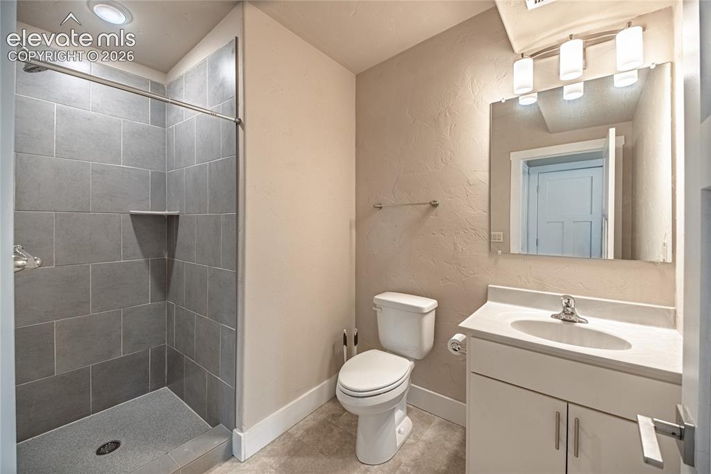 Image 41 of 50: Bathroom featuring a walk-in shower with gray tile surround and integrated