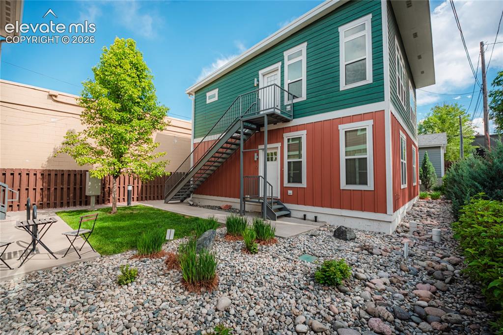 Image 46 of 50: Two-story exterior featuring vibrant green and rust-colored siding, a metal