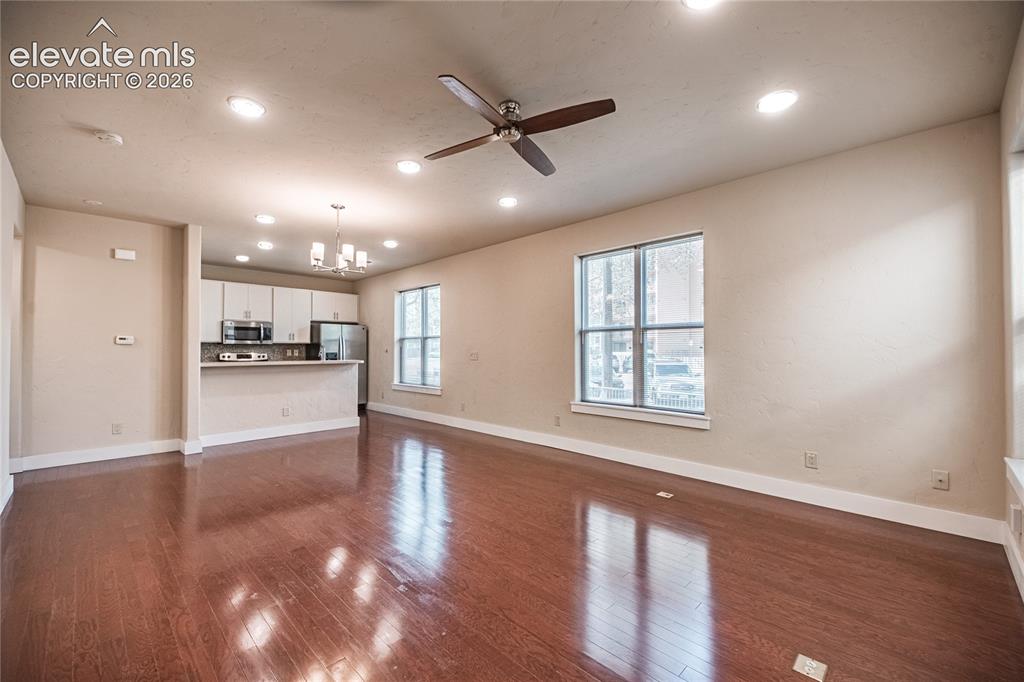 Image 9 of 50: Open-concept living space featuring wood-finish flooring, recessed lighting