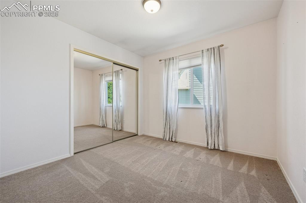 Image 12 of 27: Unfurnished bedroom featuring multiple windows, carpet flooring, and a clos