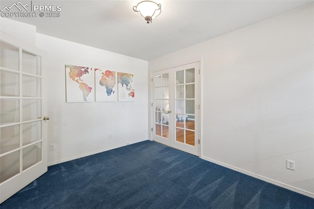 Image 14 of 27: Spare room featuring french doors and dark colored carpet