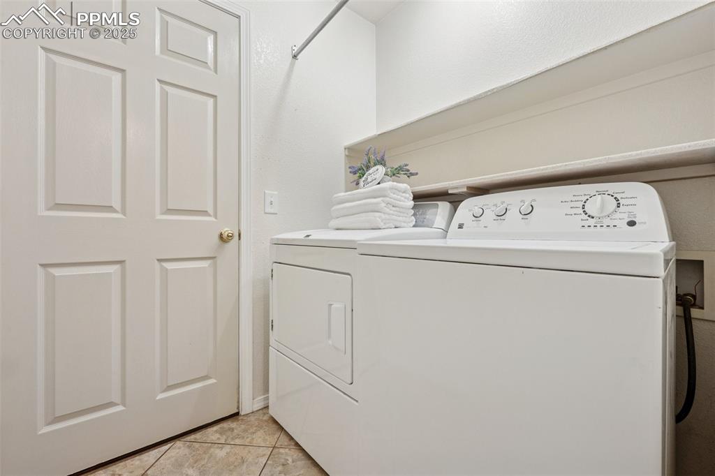 Image 15 of 27: Laundry room with light tile patterned flooring and washing machine and clo