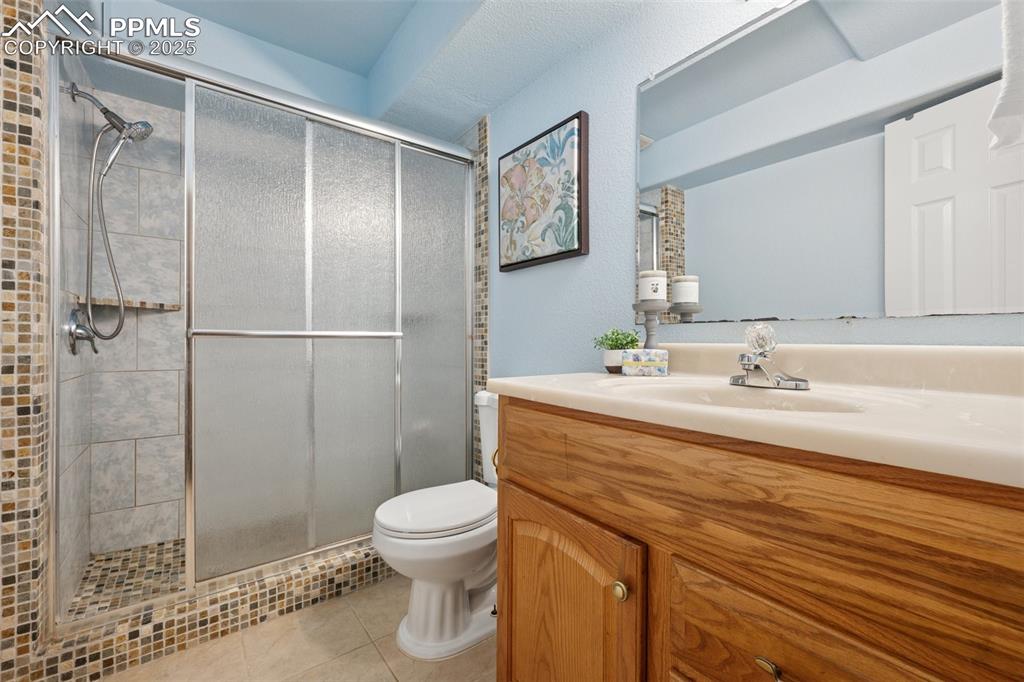 Image 22 of 27: Full bath featuring a stall shower, vanity, and light tile patterned floors