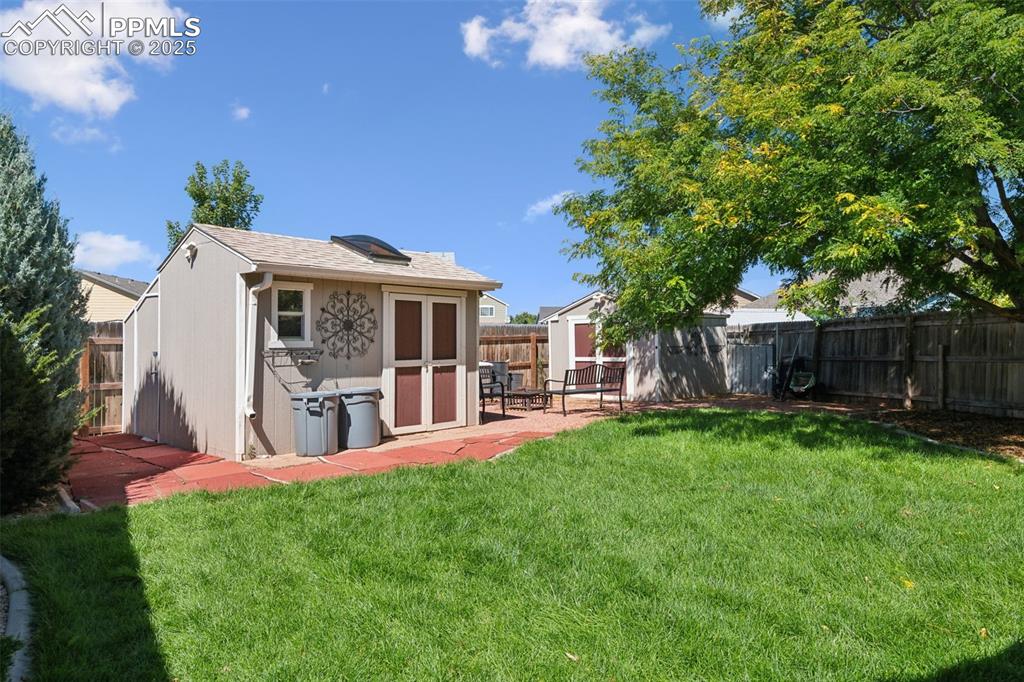 Image 23 of 27: Rear view of house with a shed, a fenced backyard, and roof with shingles