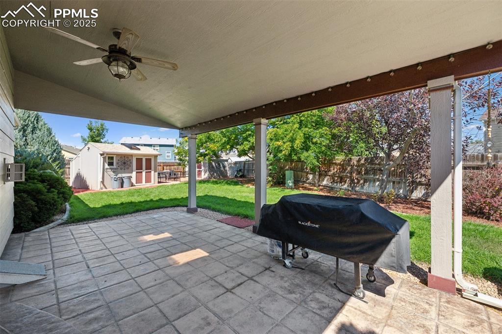 Image 25 of 27: Fenced backyard featuring a patio, an outdoor structure, a grill, and ceili