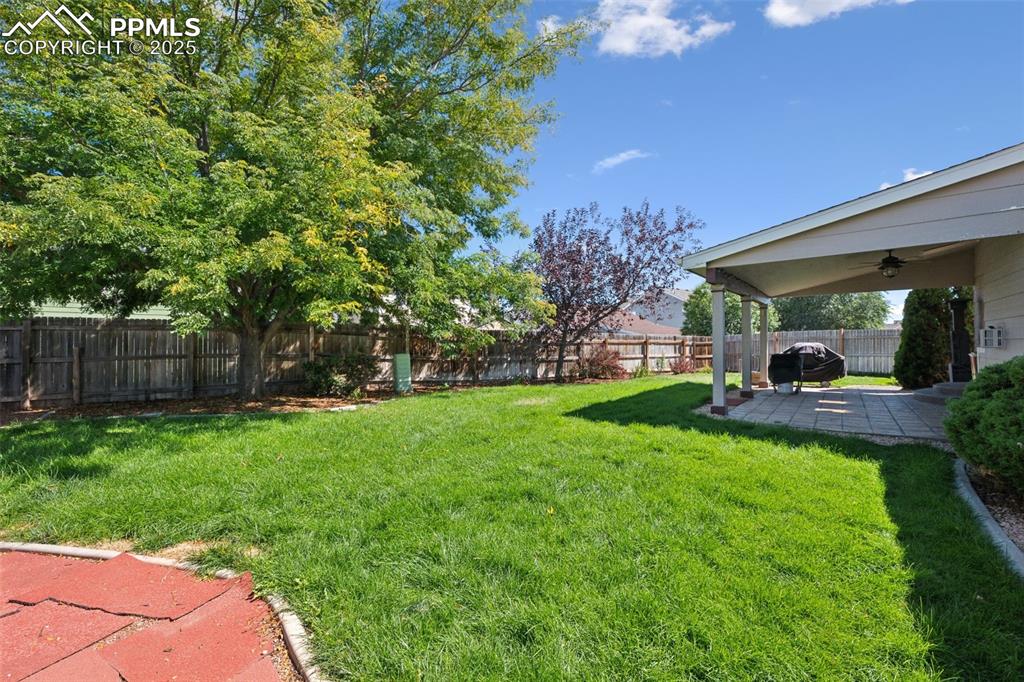 Image 26 of 27: Fenced backyard featuring a patio area and ceiling fan