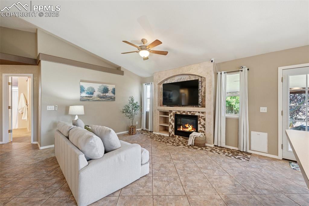 Image 4 of 27: Living room with light tile patterned flooring, ceiling fan, a fireplace, a