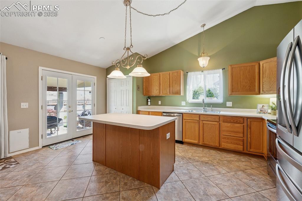 Image 6 of 27: Kitchen featuring vaulted ceiling, french doors, light countertops, a kitch
