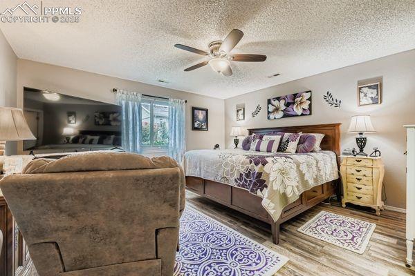 Image 12 of 15: Bedroom featuring a textured ceiling, wood finished floors, and ceiling fan